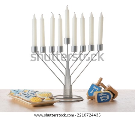Menorah with candles, cookies and dreidels for Hanukkah celebration on table against white background