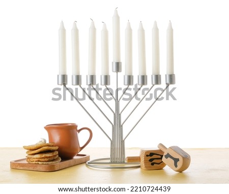 Menorah with candles, dreidels and potato pancakes for Hanukkah celebration on white background Royalty-Free Stock Photo #2210724439