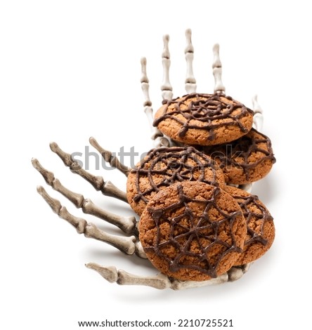 Halloween spiderweb cookies and skeleton hands on white background