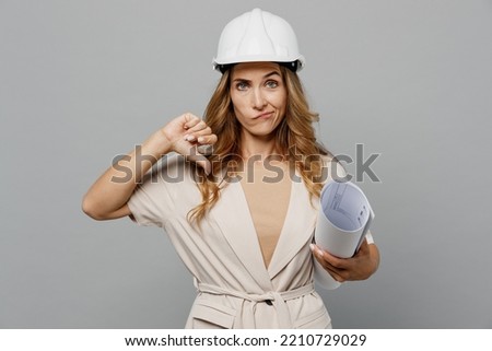 Young architect designer employee white woman wear pastel clothes hardhat hold blueprints showing thumb down isolated on plain light grey background studio portrait People work on architecture project