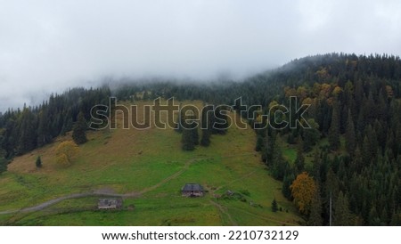 Low sky in the mountains. Autumn rain and fog on the mountain hills. Misty fall woodland.