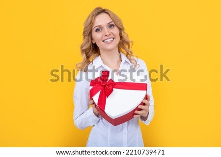 glad woman hold present heart box on yellow background