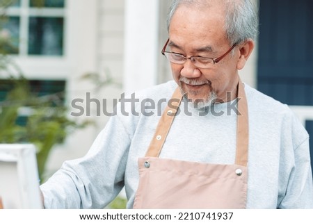 Senior painting on canvas, old man drawing in backyard garden. Senior mature artist holding color paint drawing on white paper. Elderly activitie. happy elderly. lifestyle and retirement concept.