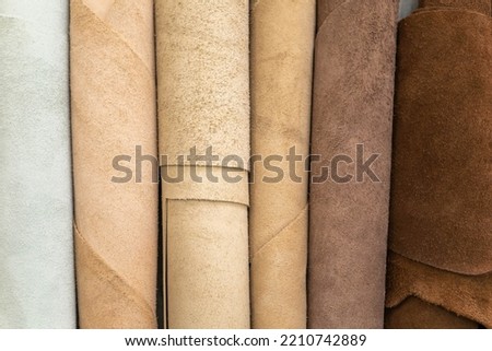 Material for creating handmade production at leather workshop. Selected pieces and bundle of beautiful colored or tanned craftman's work stuff lying inside of cupboard. 