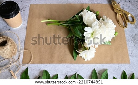 Florist makes a bouquet.a woman makes a bouquet of peonies, a bouquet of kraft paper., pruning flowers, stylite makes a bouquet