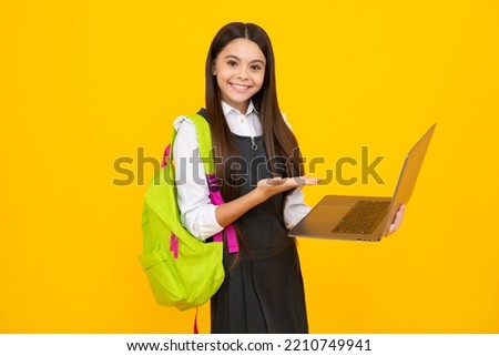 School girl hold laptop notebook on isolated studio background. Schooling and education concept. Teenager girl in school uniform. Happy girl face, positive and smiling emotions.
