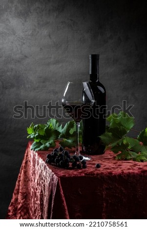 Bottle, wine in a glass and vine on a dark background.