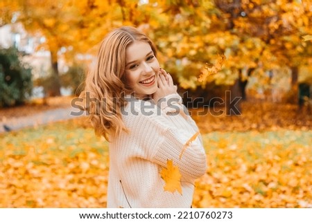 Photo portrait of a girl in a white sweater, beautiful brunette . Pretty woman in the park in autumn laughs, joy, smile. Autumn fashion and style