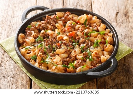 American Hamburger Goulash with Elbow Macaroni closeup in the pan on the wooden table. Horizontal
