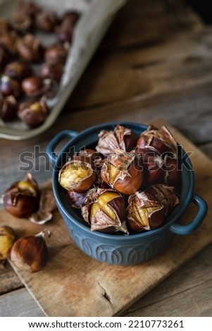 Oven roasted chestnuts with sliced peel on wooden board Royalty-Free Stock Photo #2210773261