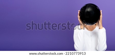 Black friday sale concept. Shopping woman holding black balloon isolated on purple background