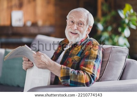 Photo of retired old man grandpa grey hair hold newspaper have break smile wear casual checkered clothes specs sit sofa indoors home room Royalty-Free Stock Photo #2210774143