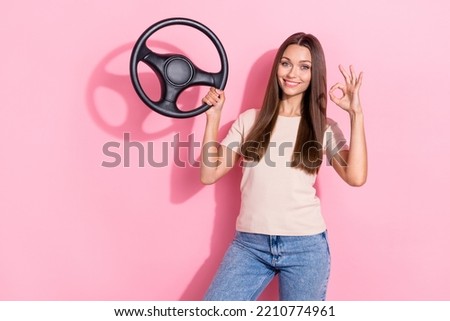 Photo of young adorable professional taxi driver woman hold her new car steering wheel after repair showing okey sign good job isolated on pink color background