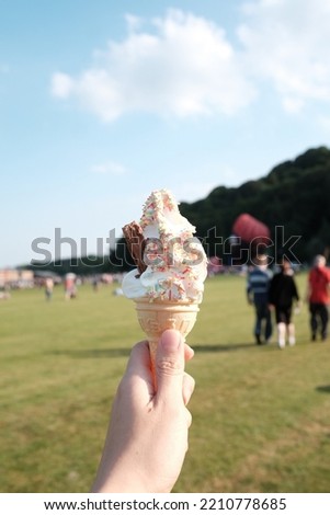 Vanilla ice cream cone, rainbow sprinkles, blurred background.