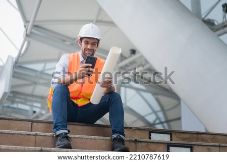 Man engineer standing on construction site. construction manager using walkie talkie. Engineer working on outdoor project and talking on phone Royalty-Free Stock Photo #2210787619