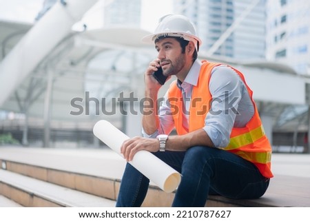Man engineer standing on construction site. construction manager using walkie talkie. Engineer working on outdoor project and talking on phone Royalty-Free Stock Photo #2210787627