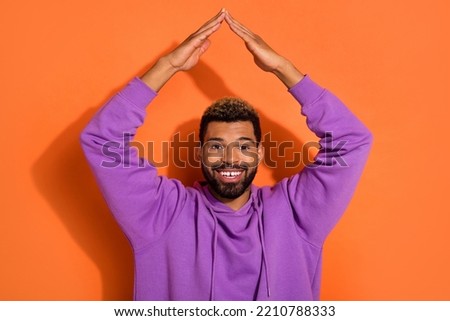Photo of funky nice dude boy model stylish pullover hold arms over head make house roof isolated on orange color background.