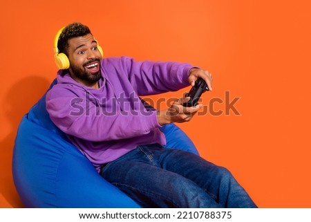 Portrait of excited carefree person addicted playing video games isolated on orange color background
