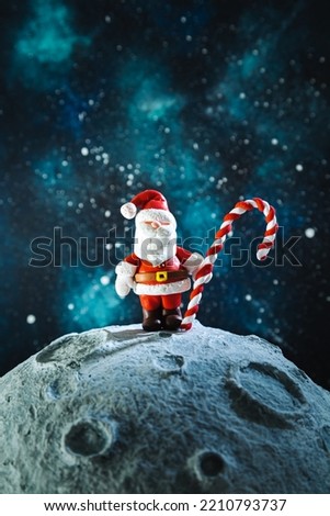 Plasticine Santa Claus with a lollipop on the moon. Christmas card.