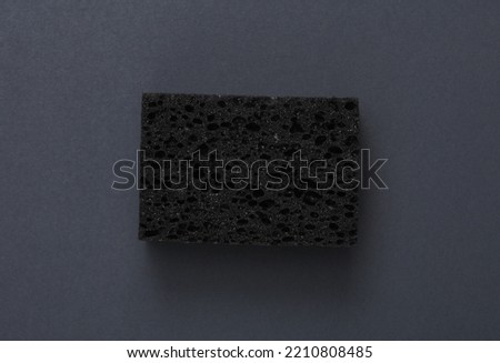 Black sponge for washing dishes on dark gray background
