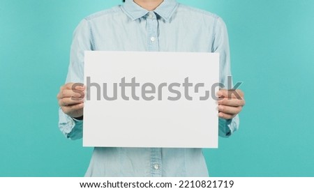 Body part of woman hands holding a white board a4 size on a green mint background.