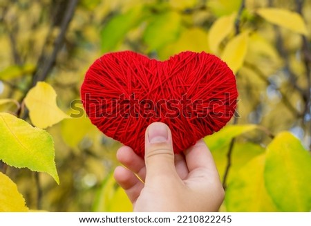 Red heart in hand against the background of autumn foliage. Gold autumn. Favorite time of year. Love autumn. 