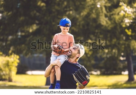 A Father and son playing baseball in sunny day at public park