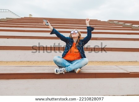 Portrait of a smiling young teenage girl sitting on a park bench and listening to music. Listening to music with headphones .generation z.