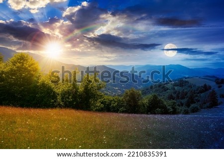 green field on the hill in mountains at twilight. day and night time change concept. wonderful carpathian countryside scenery with sun and moon. blooming herbs among the grass
