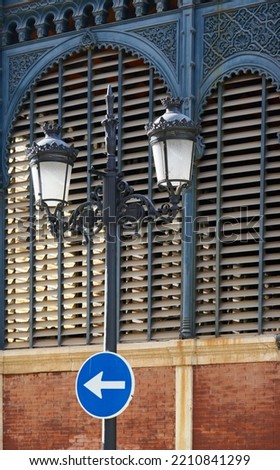 Sunset on the facade of the Atarazanas Market in Malaga. View of a decorative lamppost with a road sign with an arrow.