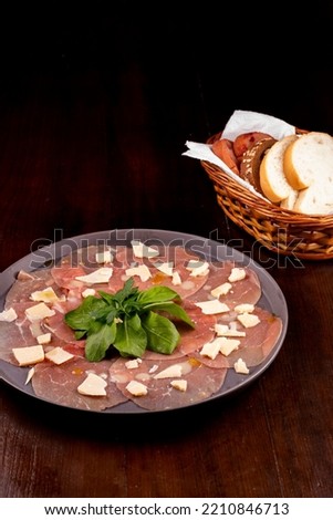 romantic dinner with carpaccio cold meats basket of artisan breads basil leaves wooden table top view portrait