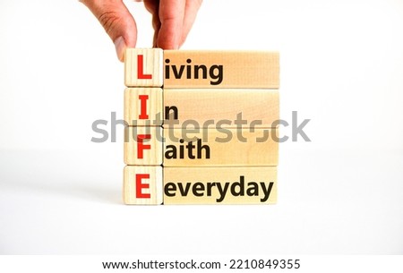 LIFE living in faith everyday symbol. Concept words LIFE living in faith everyday on wooden blocks on white background. Businessman hand. Business LIFE living in faith everyday concept. Copy space.
