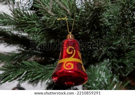 Red bell on a branch of a Christmas tree. Christmas toys on the branches of a green Christmas tree. Decorations of the New Year tree before the celebration of the new year and Christmas.