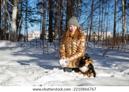 A girl in the winter in the forest rejoices in the snow and throws it up enjoying a weekend in nature in the cold