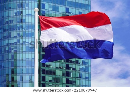 Waving in the wind flag Netherlands on the background of a modern building. Concept of politics, business and tourism in Netherlands