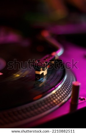 Dj turntable plays vinyl record with music. Professional disc jockey player on concert stage. Download stock photo with turn table for cover design. Turntables needle on record disc for background