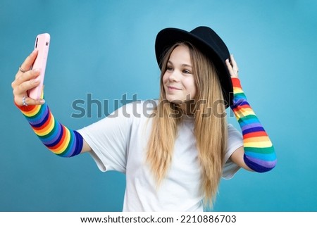 young girl in a black hat makes a selfie on a smartphone on a blue background