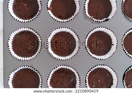 Baking chocolate cupcakes. Scooping chocolate cupcake batter into a cupcake pan.