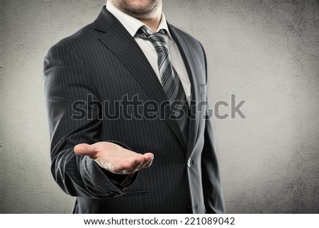 Close up portrait of businessman giving smth to his partner. Young business person in luxury stylish suit showing offer gesture.  
