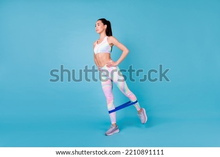 Full body photo of cute korean lady raise leg strength exercise resistance wear stylish sporty look isolated on shine blue color background Royalty-Free Stock Photo #2210891111