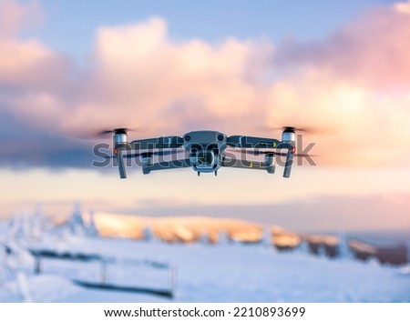 Flying drone with snowy mountains landscape and colorful clouds