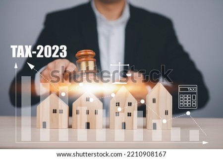 Businessman hand hold old wood Judge hammer with Mini wood home with Tax icon from model on wood table, Planning Buy Real Estate, Planning to buy property and Choose the best, taxi 2023 concept.