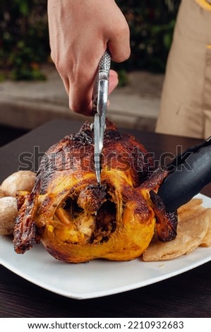 A person slices a roasted pot with kitchen scissors, to serve at a restaurant table.