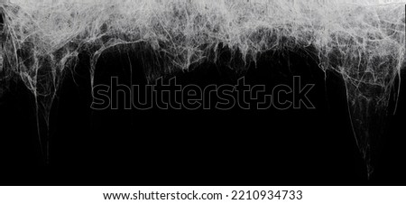 Creepy hanging spider web or cobweb on black, top border. Spooky Halloween or gothic background. Royalty-Free Stock Photo #2210934733