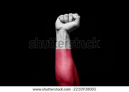 Strong man's hand in battle signal with Poland flag on black background.