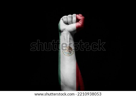 Strong man's hand in battle signal with Mexico flag on black background.