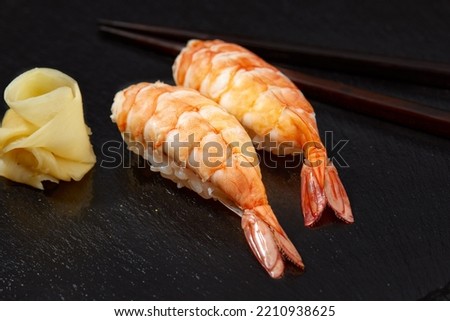 raw red shrimp nigiri photographed from above on black board, Japanese cuisine