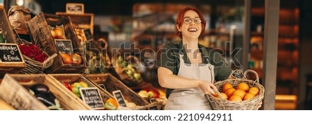 Successful grocery store owner smiling at the camera while holding a basket of fresh organic grapefruits. Happy female entrepreneur running a small business in the food industry.