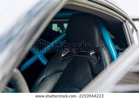 Black leather drivers seat with a blue roll cage in the background