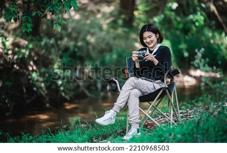 Young pretty woman use digital camera taking a photo beautiful nature while camping in forest with happiness, copy space